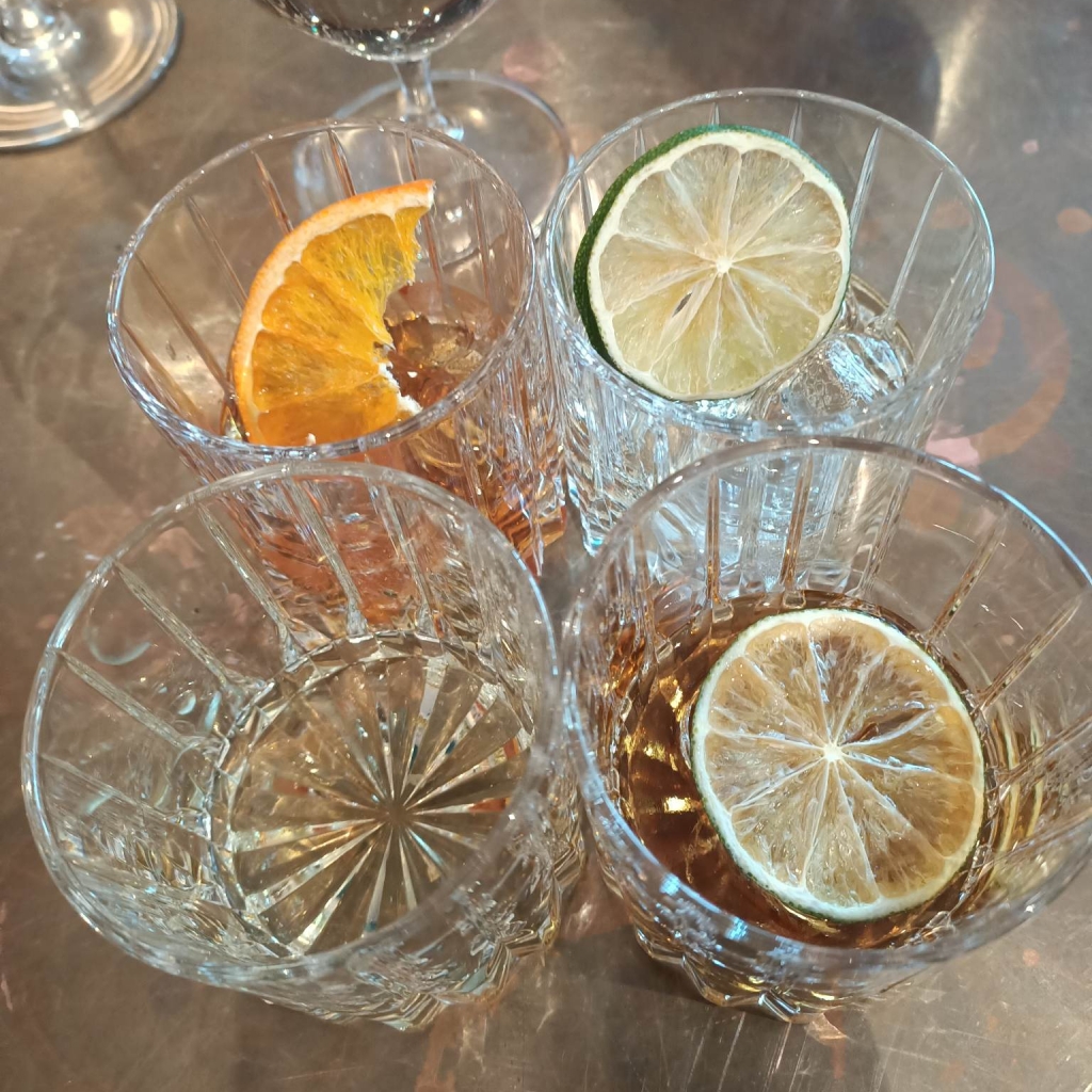 four glasses with some drink left and slices of citrus